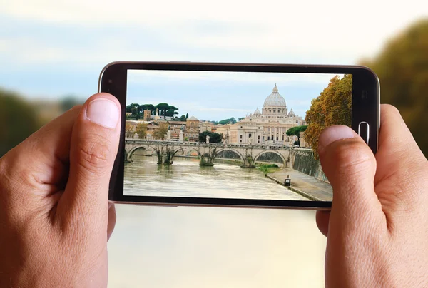 Male hand taking photo of st peter basilica in Vatican and river Tiber from the bridge in Rome with cell, mobile phone. Europe travell, Italian holiday.