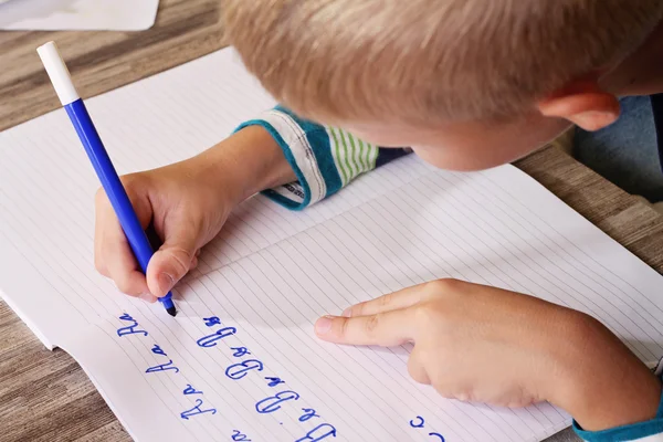 School jongen schrijven op papier het alfabet met potlood schrijven. Kind, huiswerk, onderwijs concept — Stockfoto