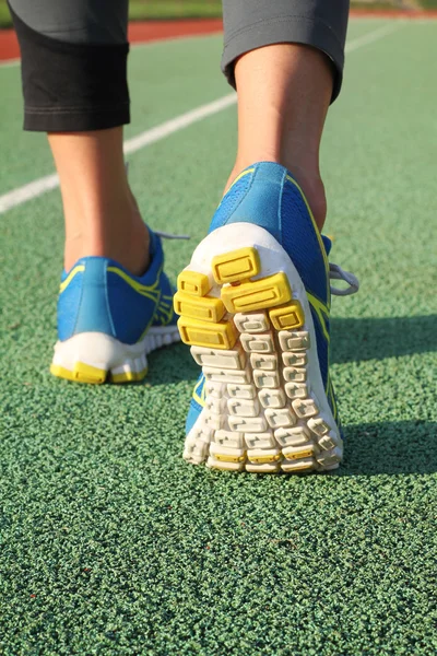 Atleta feminina correndo em pista de estádio. Fechar os sapatos e as pernas. Exercício de fitness de outono de mulher. Jogging, esporte, saudável conceito de estilo de vida ativo . — Fotografia de Stock