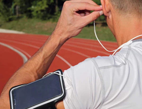 Male runner with mobile smart phone, listening to the music during workout. Running, jogging, cardio, sport, active lifestyle concept — Stock Photo, Image