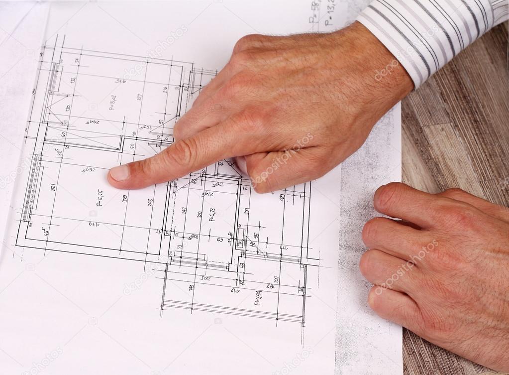 Architect showing project, house plans. Close up on male hand pointing at plan