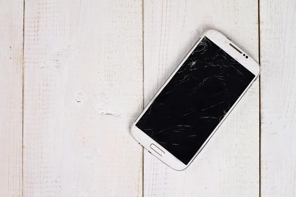 Telefon mobil alb cu ecran spart pe fundal din lemn — Fotografie, imagine de stoc