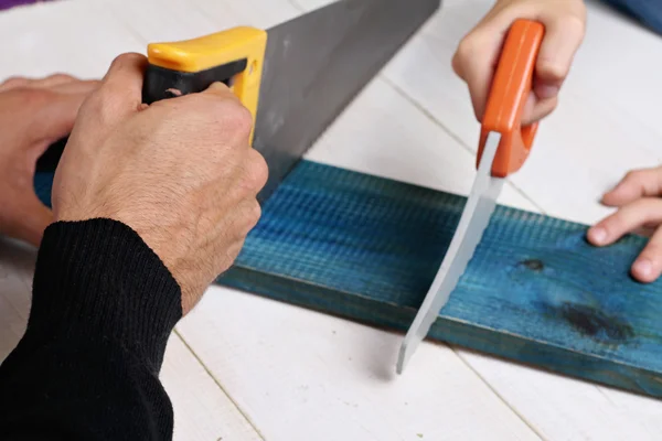 Father and son use saw. Boy helping his dad with building work at home.  Family concept. DIY tools