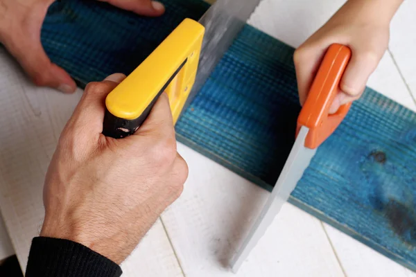 Vater und Sohn greifen zur Säge. Junge hilft seinem Vater bei Bauarbeiten zu Hause. Familienkonzept. Diy-Werkzeuge — Stockfoto