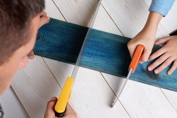 Father and son use saw. Boy helping his dad with building work at home.  Family concept. DIY tools