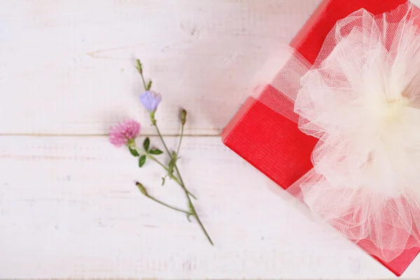 Czerwone pudełko z białej wstążki na białe drewniane opalać. Opakowaniu prezent. Urodziny, Sylwester, Walentynki, 8 marca, Christmas koncepcji. Prosty elegancki styl — Zdjęcie stockowe
