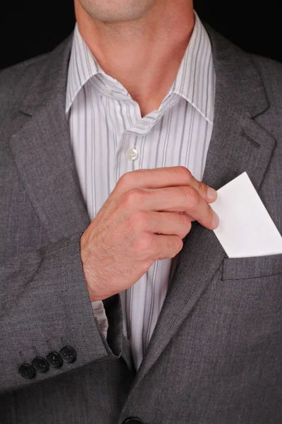 Hombre de negocios poniendo una tarjeta de visita en blanco en el bolsillo de su traje. Primer plano de un hombre de negocios tomando una tarjeta de visita del bolsillo del pecho de su chaqueta de traje . — Foto de Stock