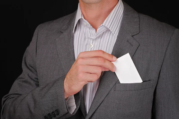 Business man putting a blank business card in his suit pocket. Closeup of a businessman taking a business card from the breast pocket of his suit jacket. — Stok fotoğraf