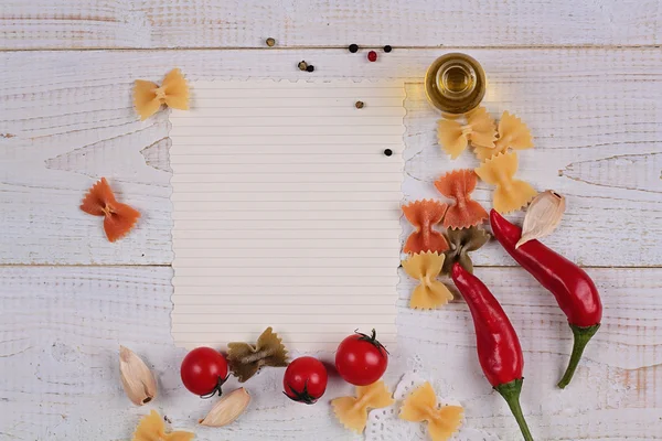 Madlavning baggrund. Tomater, rød peber og Farfalle Pasta og blankt papir på hvidt rustikt træbord. Italiensk køkken Opskrift Planlægning koncept - Stock-foto