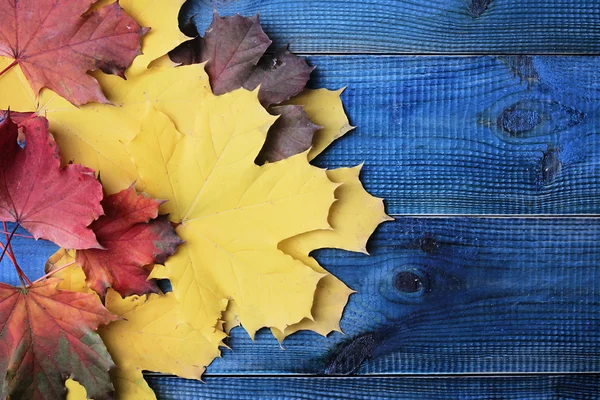 Żółte i czerwone autumn listowie na niebieskim tle rustykalnym. Sezon tapeta — Zdjęcie stockowe