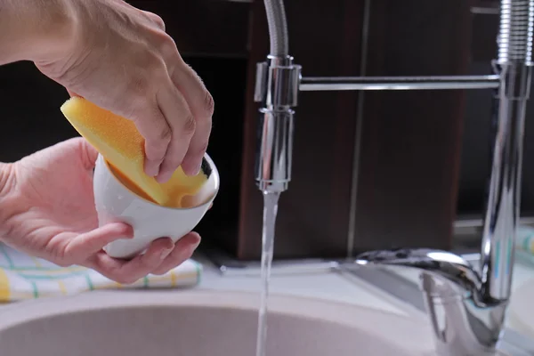 Primer plano de las manos de la mujer lavando los platos por esponja, grifo de cocina moderna y fregadero. Limpieza del hogar y concepto de higiene del hogar —  Fotos de Stock