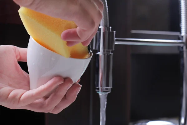 Close up de mãos de mulher lavar pratos por esponja, torneira de cozinha moderna e pia. Limpeza da casa e conceito de higiene doméstica — Fotografia de Stock