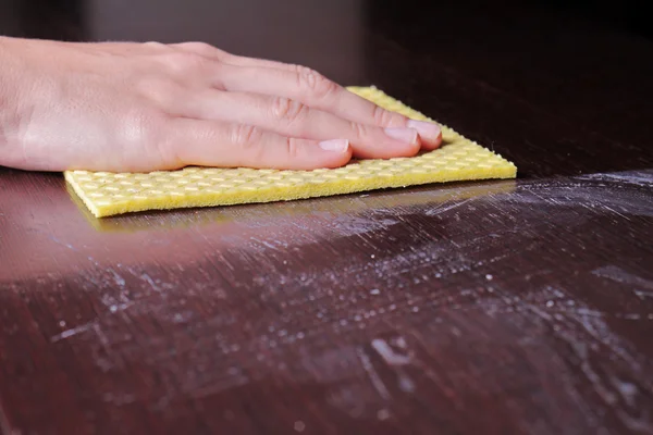 Nahaufnahme von Hand reinigen Holztisch mit Möbelpolitur. mit gelbem Schwamm zur Reinigung staubigen Holzes. Hausreinigung und Hygienekonzept — Stockfoto