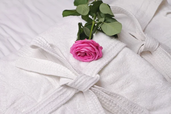 Montón de toallas de hotel blancas y suaves y albornoz decorado con flor de rosa. Perfecta ropa blanca. Spa, estilo de vida saludable y concepto de relajación. Concepto de luna de miel . — Foto de Stock