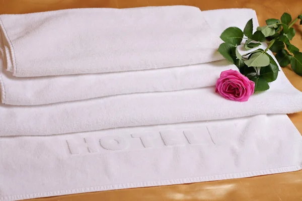 Montón de toallas de hotel blancas y suaves decoradas con flor de rosa. Perfecta ropa blanca. Concepto de luna de miel — Foto de Stock