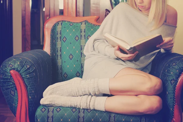 Mooie gezellige vrouw lezen van een boek ontspannen in comfortabele fauteuil zit. Kerst vakantie concept. — Stockfoto