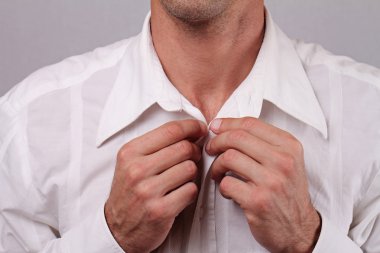 Close up of young man businessman  buttoning up white shirt. Groom preparing for wedding. Perfect white laundry