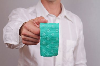 Close up on man hands holding pick up poop bags for dogs. Please Clean up after your dog concept