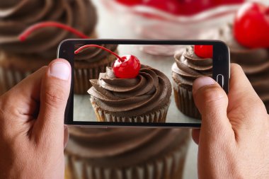 Erkek el alarak fotoğraf kiraz ile cep, cep telefonu ile çikolatalı kek.