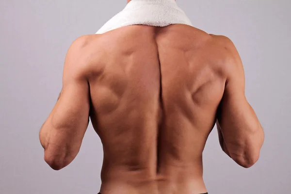 Back view of strong muscular male body, closeup of fitness man with a white towel slung around his neck. bodybuilding, work out, sport, hard work, motivation, active lifestyle concept