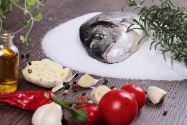 Fresh raw sea bream fish on salt decorated with lemon and herbs on blue wooden background. Healthy food concept