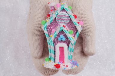 Candyland Noel. Erkek içinde beyaz örme rahat mittens renkli şeker ev Noel ağacı decorationon beyaz kar arka planda tutan eller. Kış, yeni yıl ve Noel zamanı