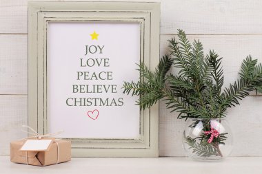 Christmas poster in  shabby chik frame,  fir branch and vintage gift box with with copy space blank tag on white background. Scandinavian style home interior decoration clipart