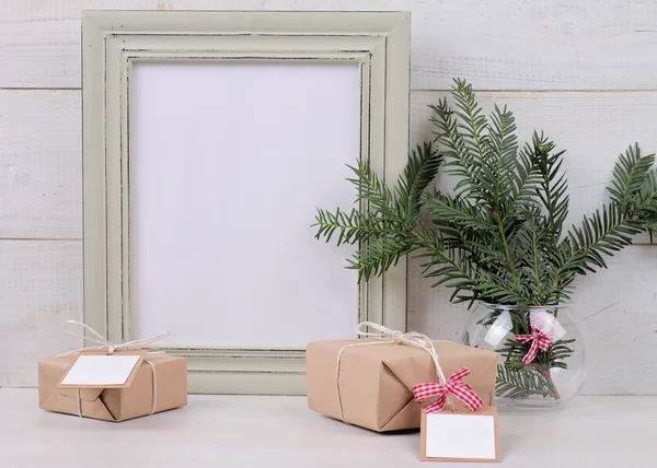 Christmas and New Year background. Empty picture frame,  fir branch and vintage gift box with with copy space blank tag on white background. Scandinavian style home interior decoration