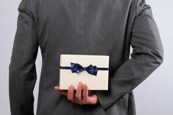 Man hiding a gift box behind his back close up. — Stock Photo, Image