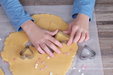 Child making heart shaped cookies close up. Surprise present ideas for mother birthday or mother's day
