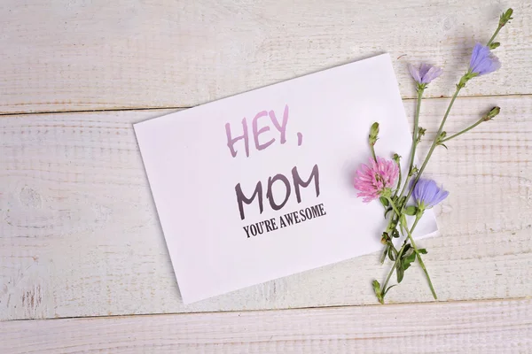 Hey, Mom , Your are awesome message card and bouquet of flowers on rustic wooden table. Funny valentine card for mother, birthday card, funny mother's day card