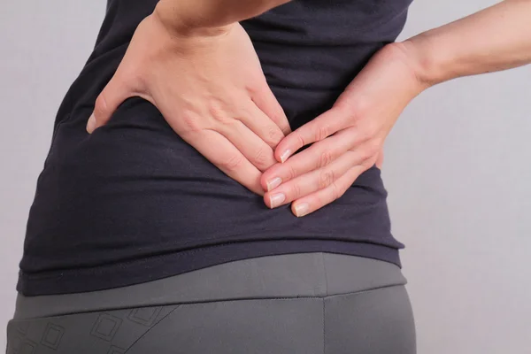 Dolor de espalda. Mujer atlética de fitness frotando los músculos de su espalda baja. Lesiones por ejercicio deportivo. — Foto de Stock