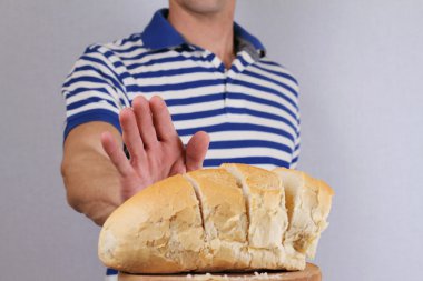 Gluten Hoşgörüsüzlük ve diyet kavramı. Adam beyaz ekmek yemeyi reddediyor. Seçici odak ekmek üzerinde