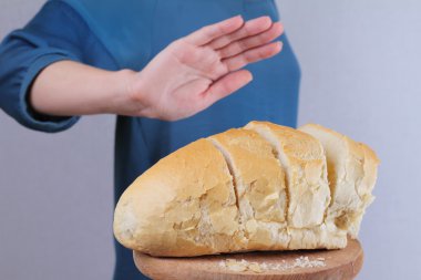 Gluten intolerance and diet concept. Woman refuses to eat white bread. Selective focus on bread clipart