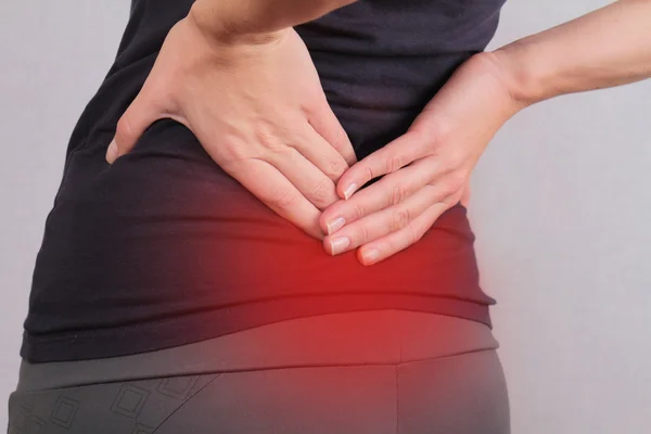 Dolor de espalda. Mujer atlética de fitness frotando los músculos de su espalda baja. Lesiones por ejercicio deportivo. — Foto de Stock