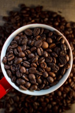 Kahve çekirdekleri fincanda ve masanın üzerinde.