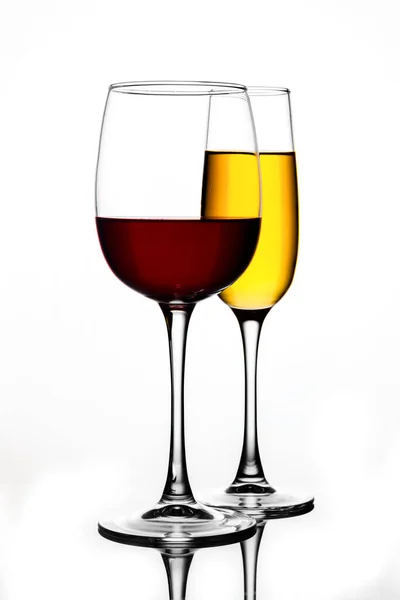 Бокалы различных форм с разноцветными напитками на белом фоне с отражением — стоковое фото