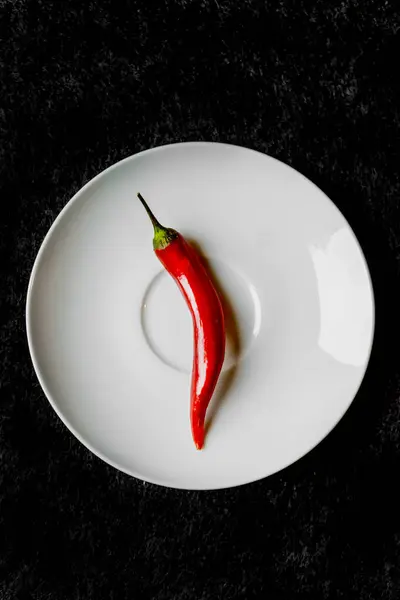 Röd paprika på en tallrik på en mörk bakgrund — Stockfoto