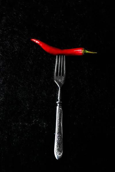 Metallgaffel med peppar på en mörk bakgrund — Stockfoto