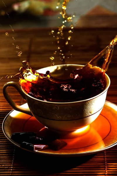 Un chorrito de té vertido en una taza en un platillo — Foto de Stock