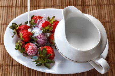 Çilekler süt testisiyle tepside kremayla doldurulur.