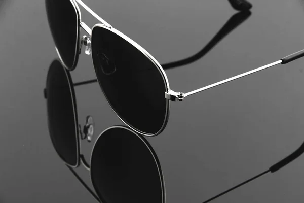 Silver-rimmed sunglasses with reflection on dark background — Stock Photo, Image