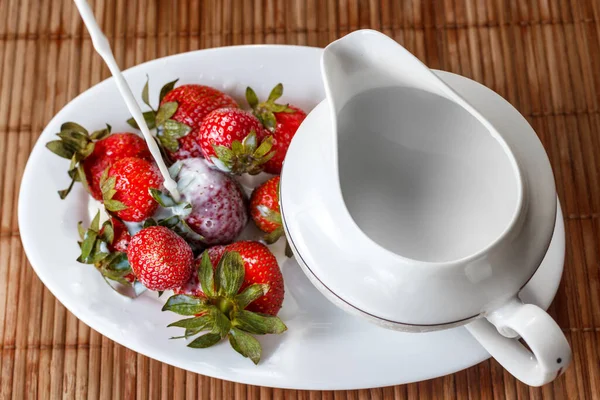 Strawberries are poured with cream on a tray with milk jug — Stock Photo, Image