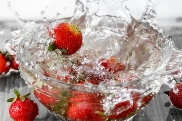 Jordgubbar som faller i vatten med spray — Stockfoto