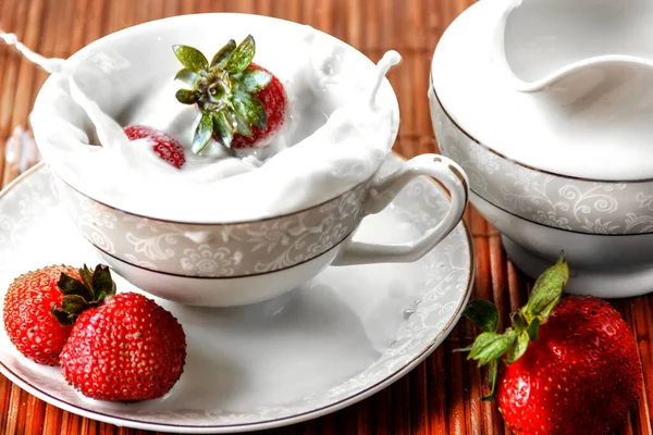 Eine Tasse Milch und Erdbeeren fallen hinein — Stockfoto