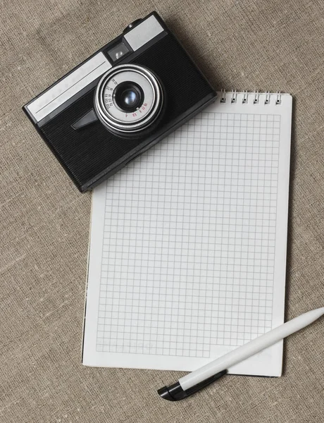 Hintergrund. Ein Blatt aus einem Notizbuch mit einem Stift und einer darauf liegenden Kamera — Stockfoto