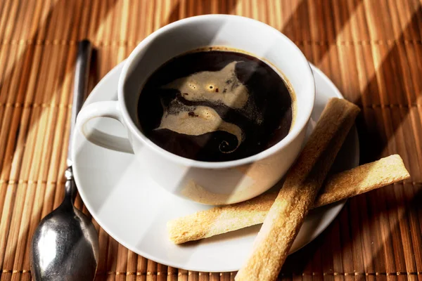 Tasse schwarzen Kaffee auf einer Untertasse mit Keksen — Stockfoto