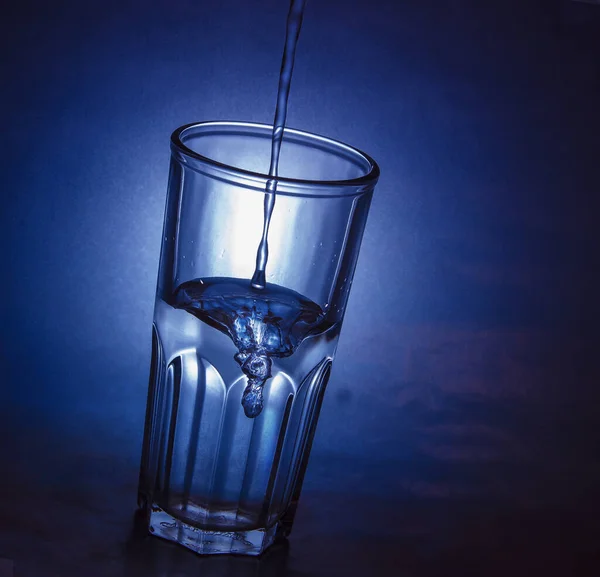 Szkło wypełnione wodą na niebieskim tle — Zdjęcie stockowe