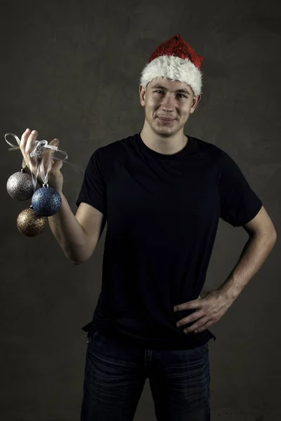 Jeune homme avec des boules de Noël dans une casquette du Nouvel An. Vacances. Nouvel An — Photo