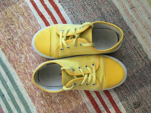 Желтые кроссовки на сотканном разноцветном ковре — стоковое фото